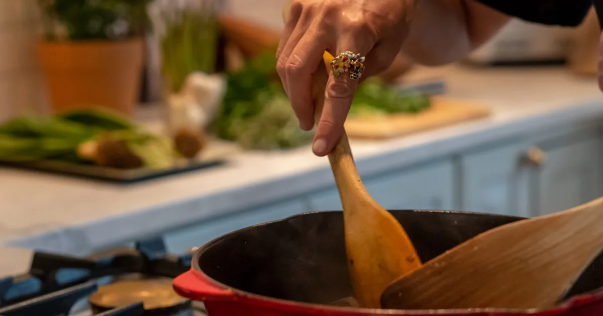 Pessoa mexendo panela com colher de pau no fogão, preparando doce