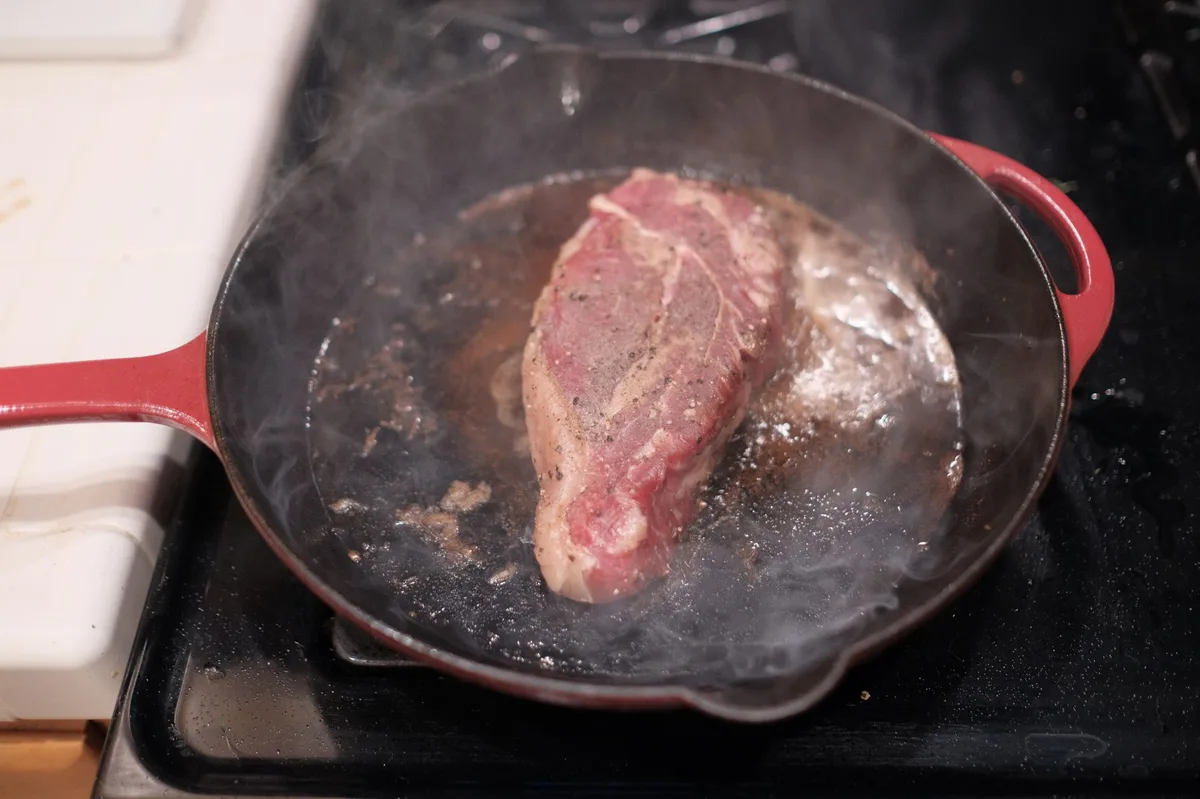 Carne sendo frita em frigideira quente com coloração dourada