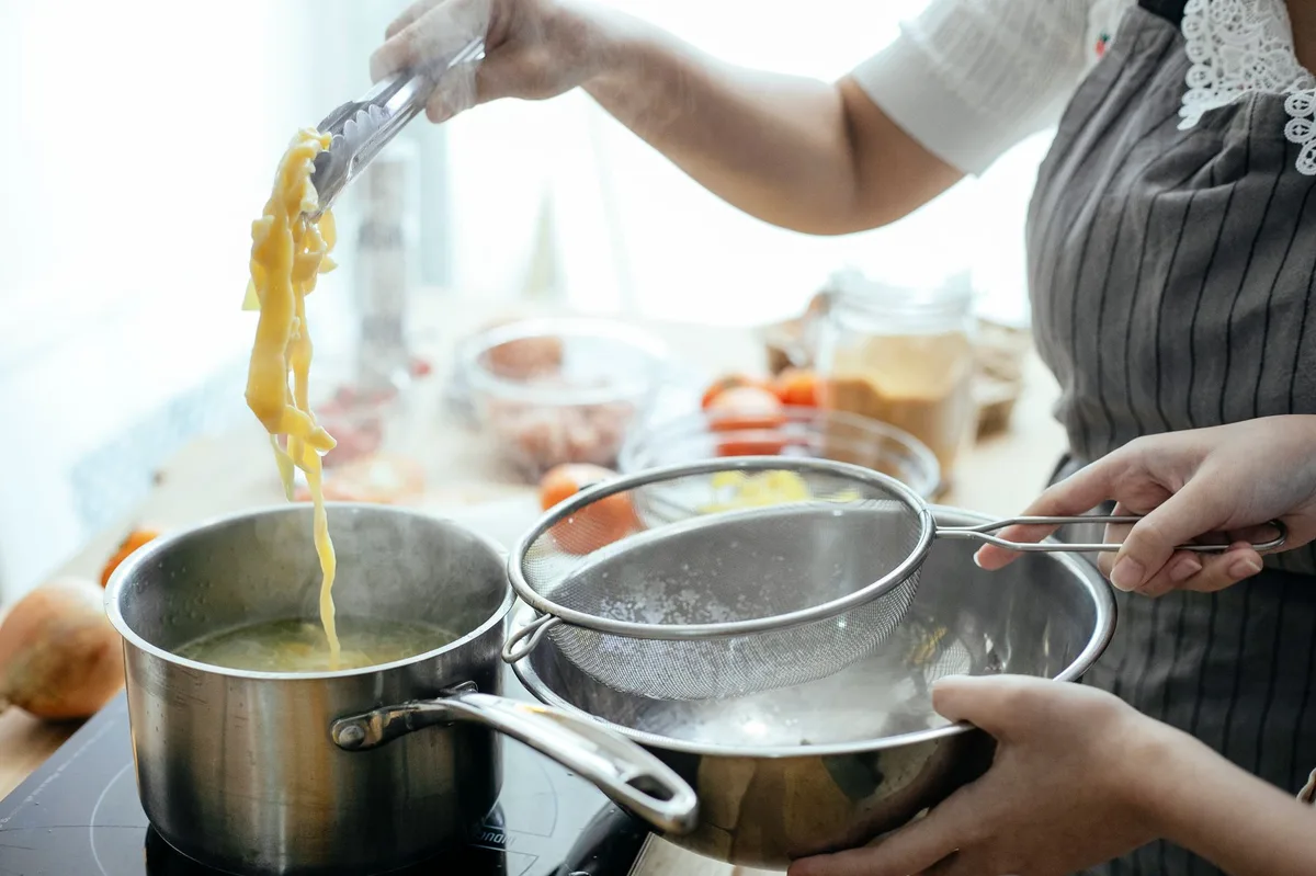 Macarrão sendo cozinhado em panela no fogão com água fervente