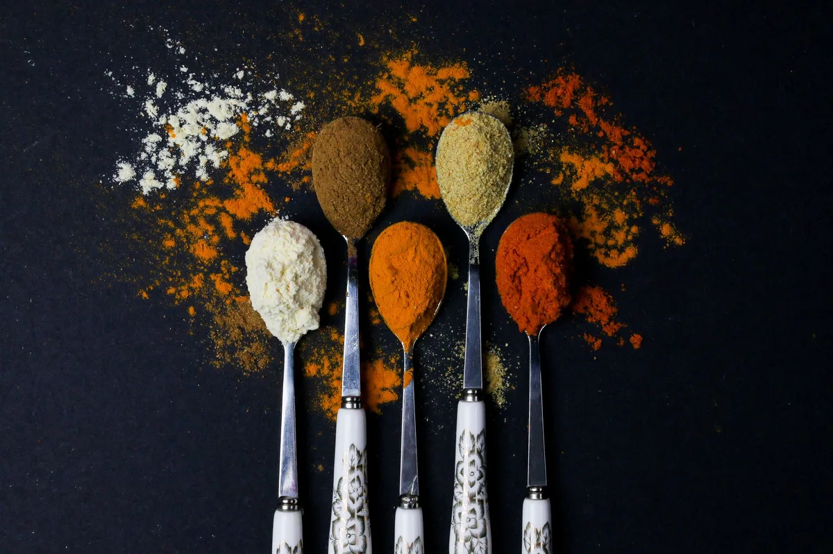 Colheres com temperos coloridos variados sobre uma superfície