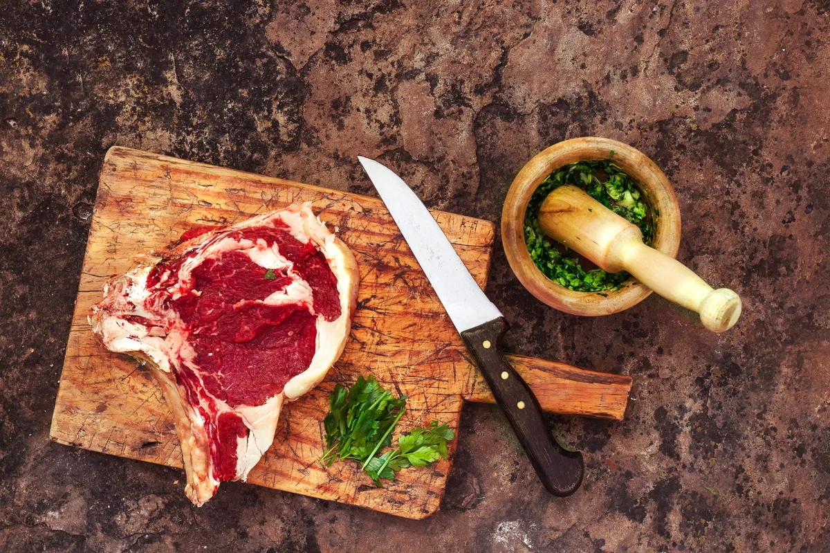 Temperos variados dispostos sobre tábua de madeira, prontos para temperar carne