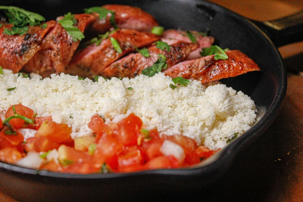 Pessoa mexendo ingredientes dourados em uma panela com colher de pau no fogão