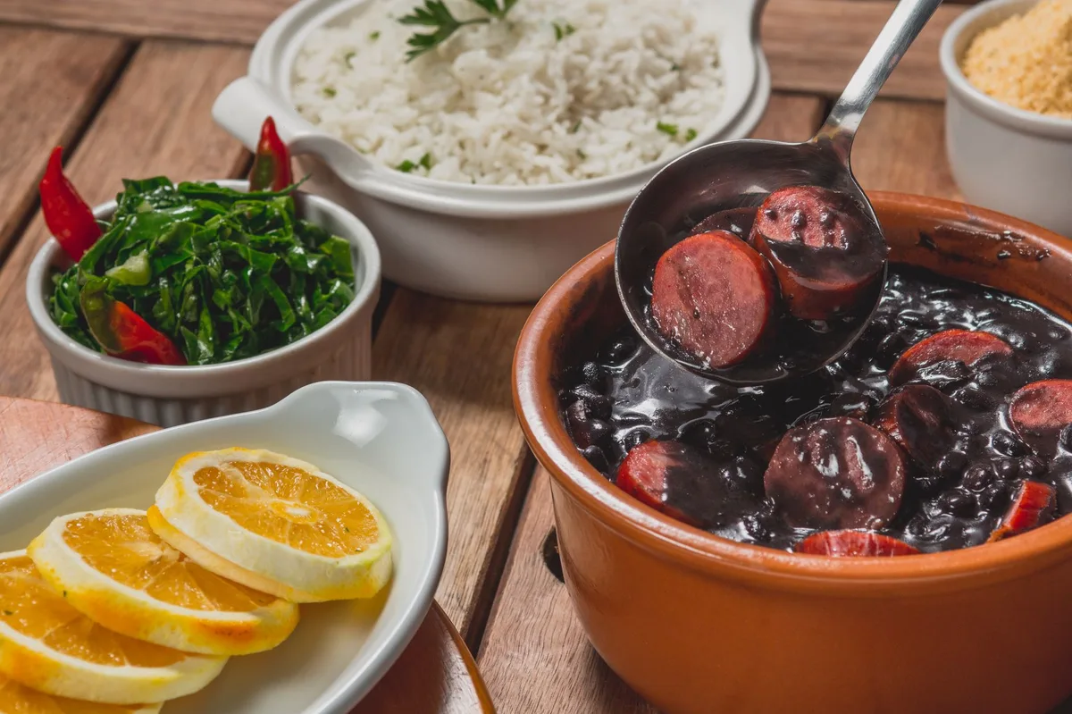 Feijão cozido em tigela sobre tábua de madeira, ingrediente principal do feijão tropeiro