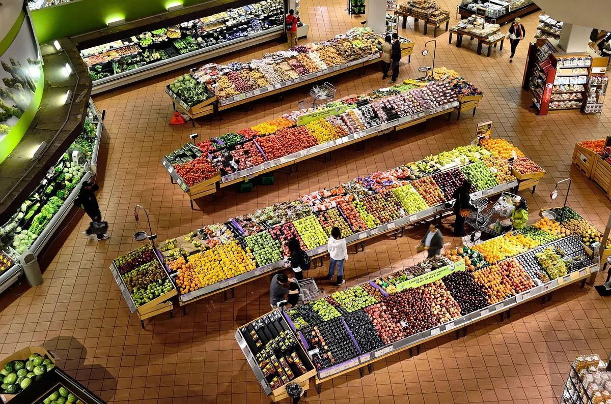Banca de feira ao ar livre repleta de legumes frescos e coloridos organizados em caixas de madeira