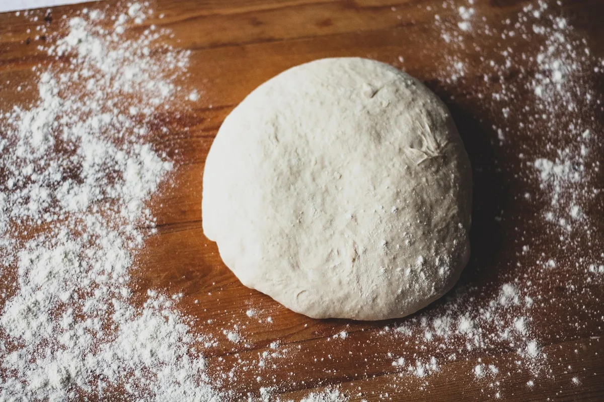 Massa de pão sobre mesa de madeira pronta para assar