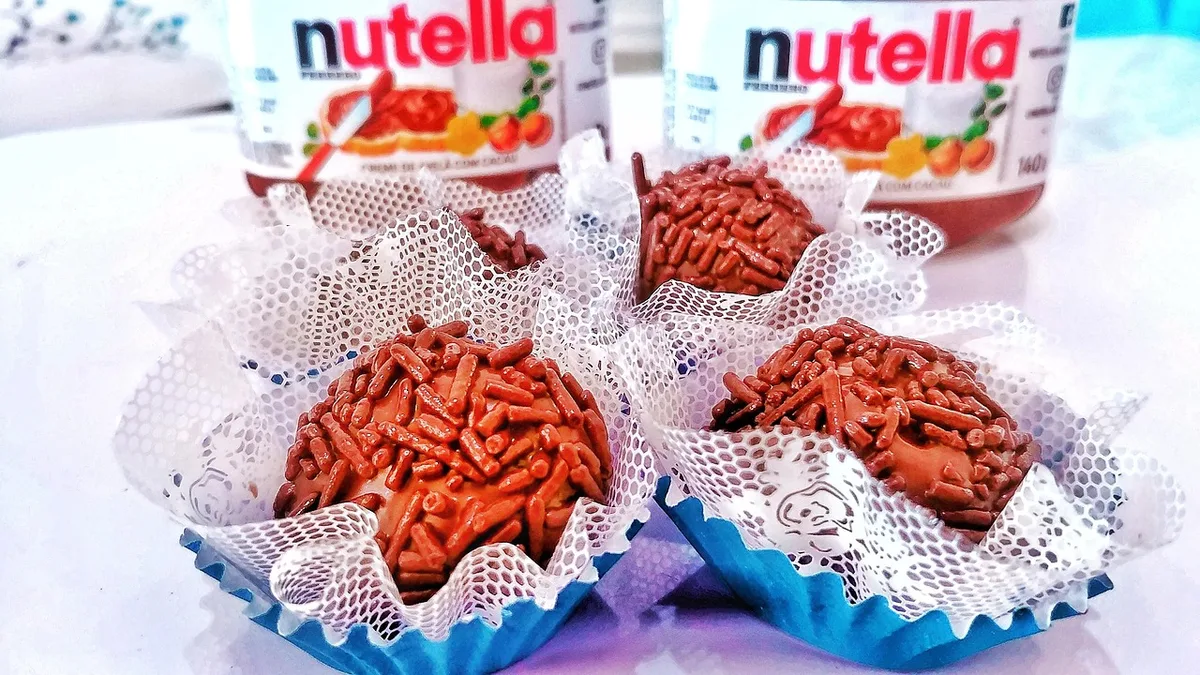 Pessoa mexendo brigadeiro em uma panela com colher de pau no fogão