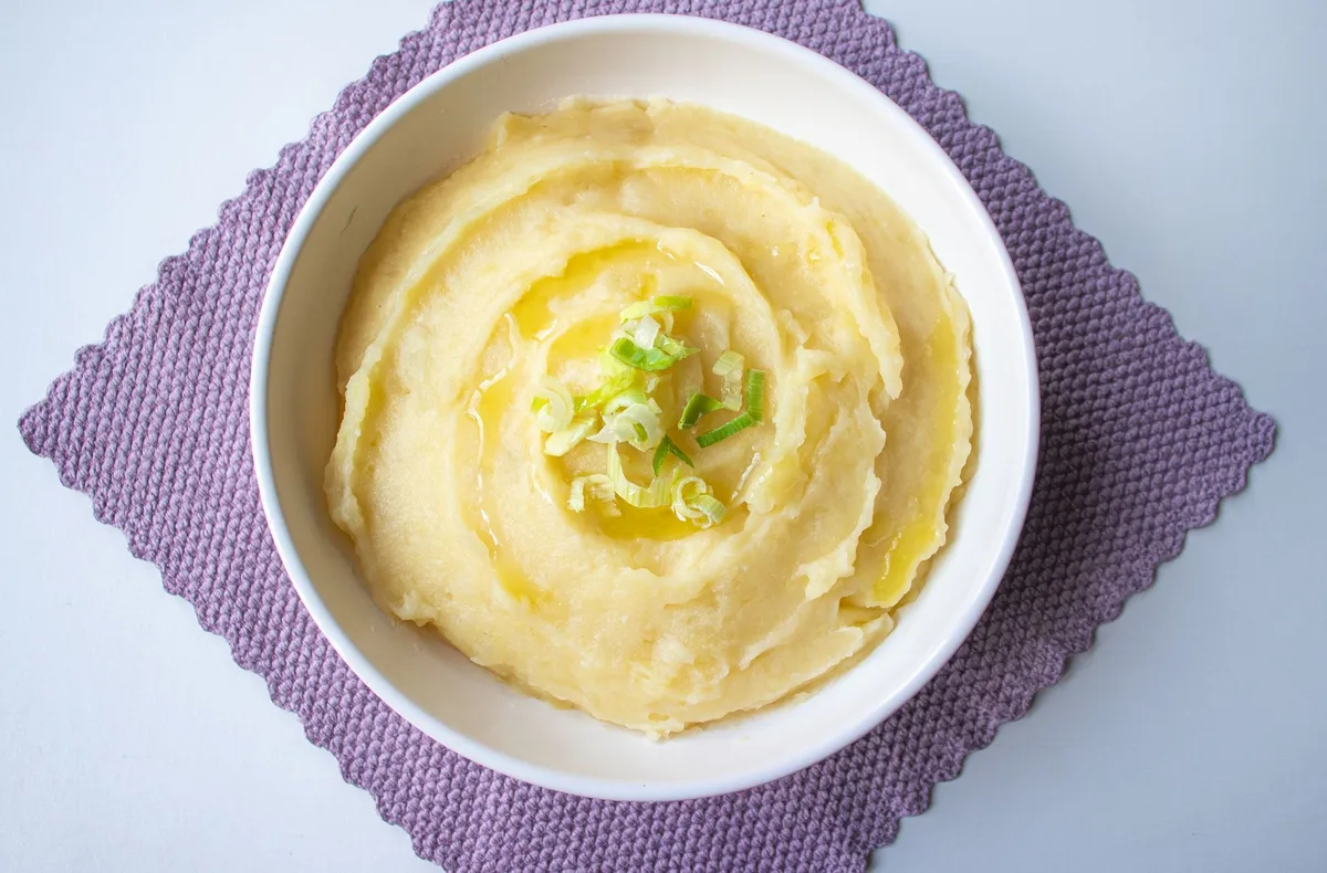 Purê de batata cremoso servido em tigela branca, mostrando textura lisa e aveludada