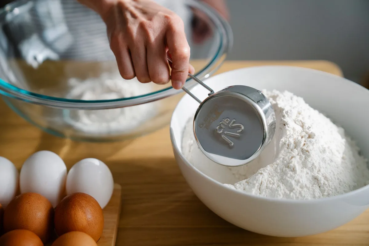 Pão caseiro polvilhado com farinha de trigo sobre superfície de madeira