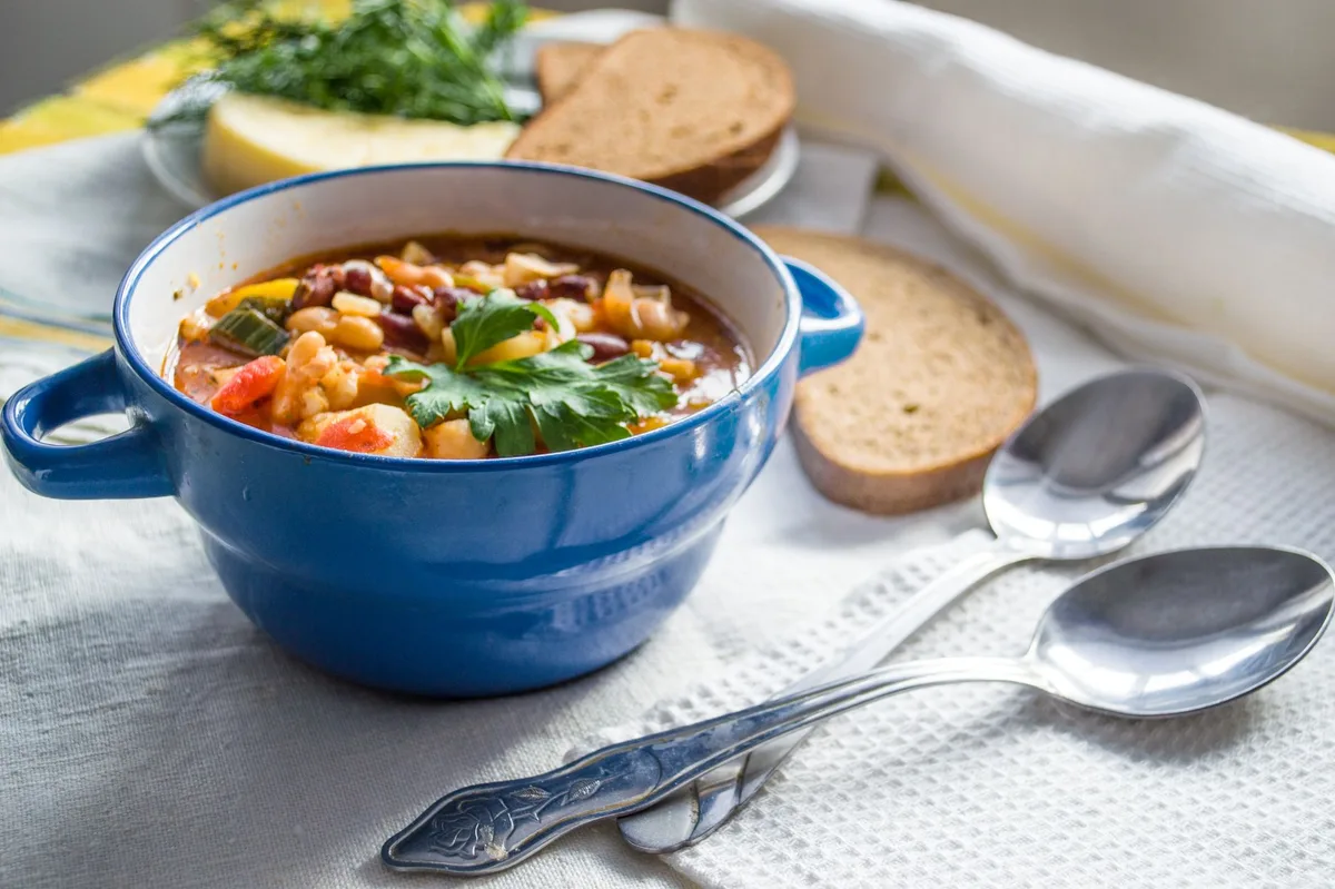 Tigela branca com sopa de legumes e colher, vista de cima